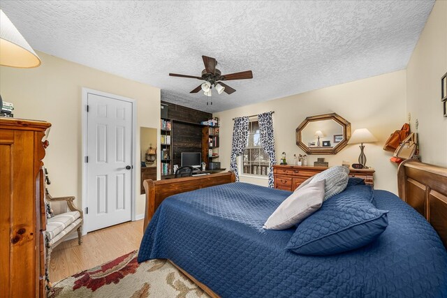 bedroom featuring a textured ceiling, light wood finished floors, and a ceiling fan