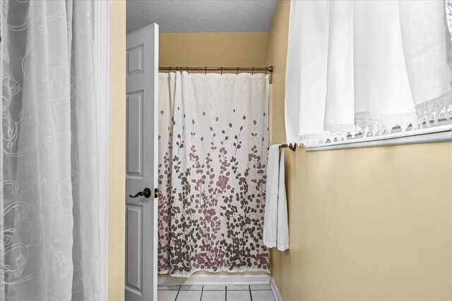 full bath featuring a textured ceiling and tile patterned floors