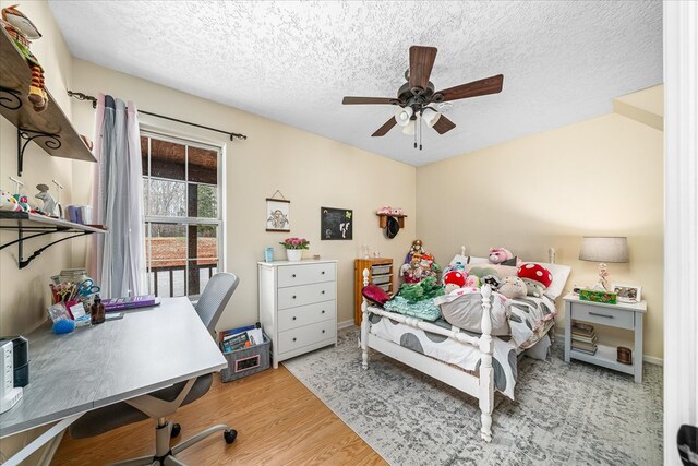 bedroom with a ceiling fan, a textured ceiling, and wood finished floors