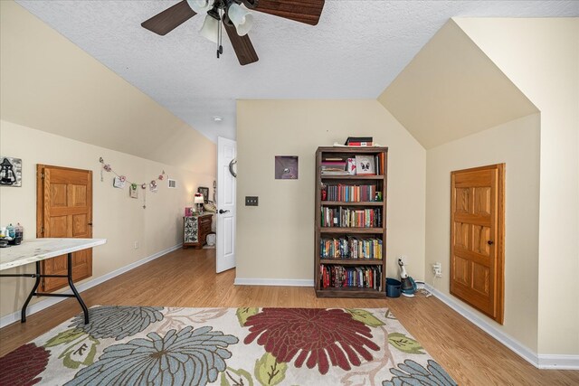 living area with lofted ceiling, light wood-style floors, and baseboards