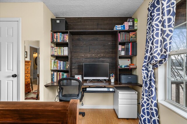 office space with wood walls, a textured ceiling, and wood finished floors