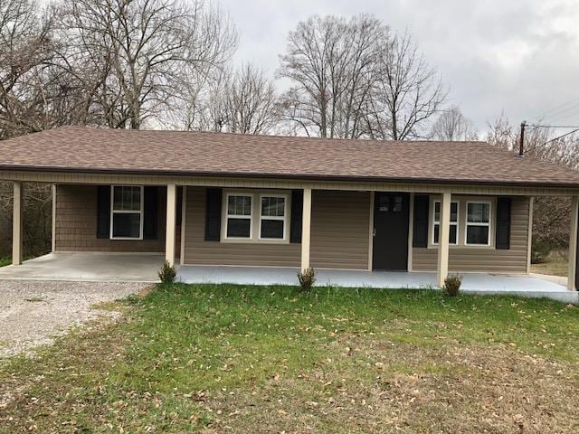 ranch-style home with covered porch, a shingled roof, and a front lawn