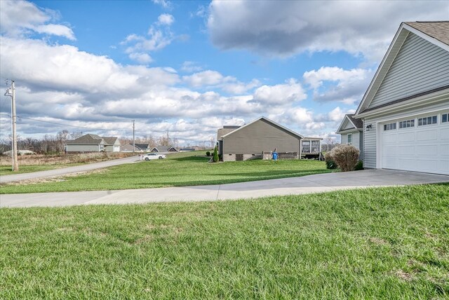 view of yard with a garage and concrete driveway