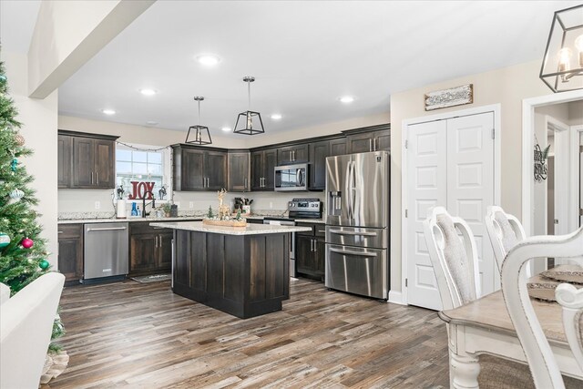 kitchen with dark brown cabinetry, stainless steel appliances, pendant lighting, and a center island