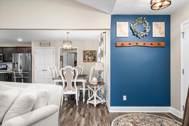 dining space with dark wood-type flooring, a chandelier, and baseboards