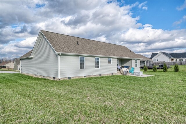 rear view of property with crawl space, a patio area, a yard, and roof with shingles