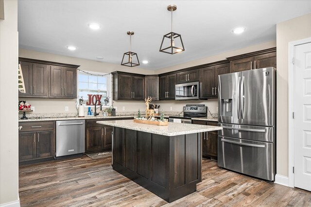 kitchen with appliances with stainless steel finishes, pendant lighting, a kitchen island, and dark brown cabinets