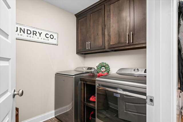 laundry area featuring cabinet space, baseboards, washer and clothes dryer, and wood finished floors