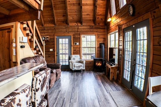 unfurnished living room featuring dark wood finished floors, beam ceiling, wood walls, and stairway