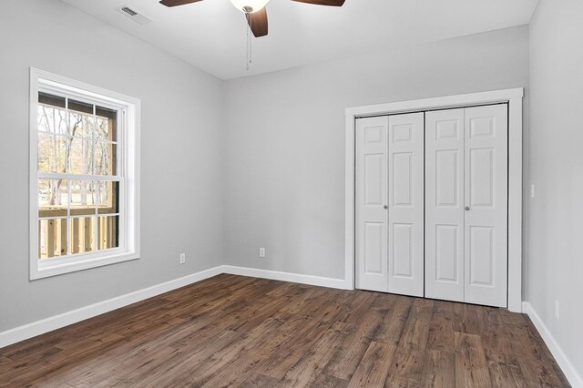 unfurnished bedroom with a ceiling fan, visible vents, baseboards, a closet, and dark wood finished floors