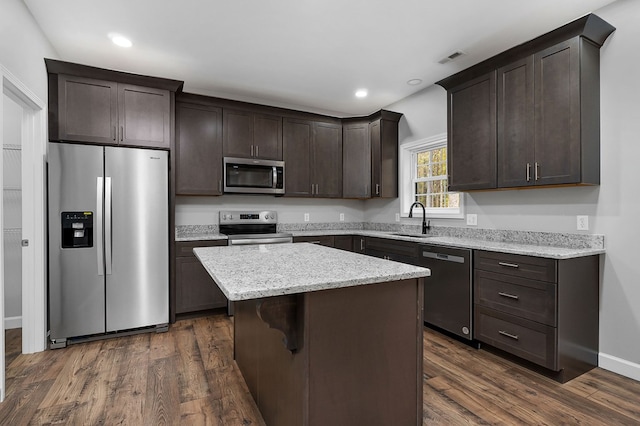 kitchen featuring stainless steel appliances, dark wood-type flooring, a kitchen island, a sink, and visible vents