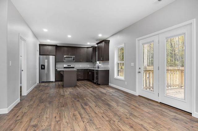 kitchen featuring light countertops, appliances with stainless steel finishes, dark wood-type flooring, a kitchen island, and dark brown cabinets