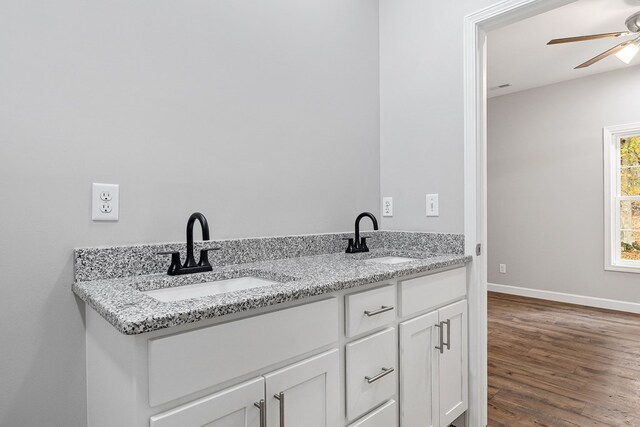 bathroom featuring wood finished floors, double vanity, a sink, and ceiling fan