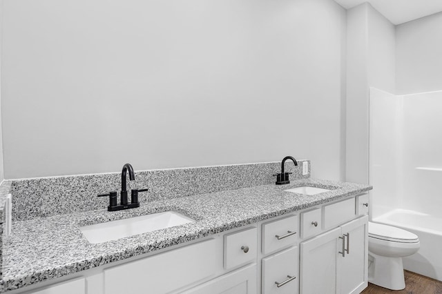 full bathroom with double vanity, toilet, a sink, and wood finished floors