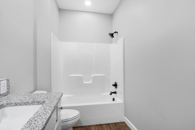 bathroom with bathtub / shower combination, toilet, wood finished floors, vanity, and baseboards