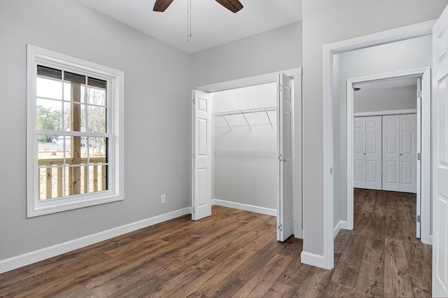 unfurnished bedroom featuring dark wood-style flooring, a closet, a ceiling fan, and baseboards