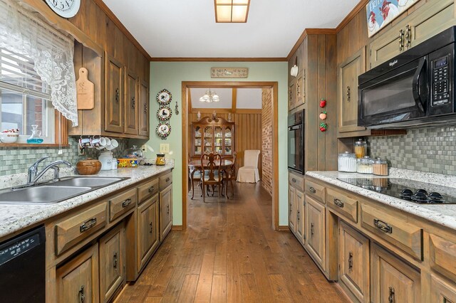 kitchen featuring dark wood-style floors, light stone counters, brown cabinets, black appliances, and a sink