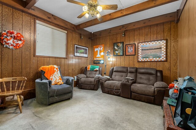 living room featuring ceiling fan, carpet flooring, beam ceiling, and wooden walls