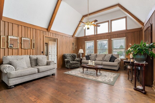 living room featuring ceiling fan, wooden walls, and dark wood finished floors