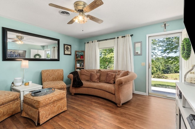 living room with a ceiling fan, baseboards, visible vents, and wood finished floors