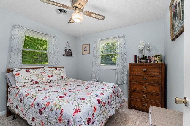 bedroom featuring baseboards, a ceiling fan, visible vents, and light colored carpet