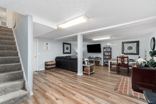 living area featuring baseboards, a textured ceiling, stairway, and wood finished floors