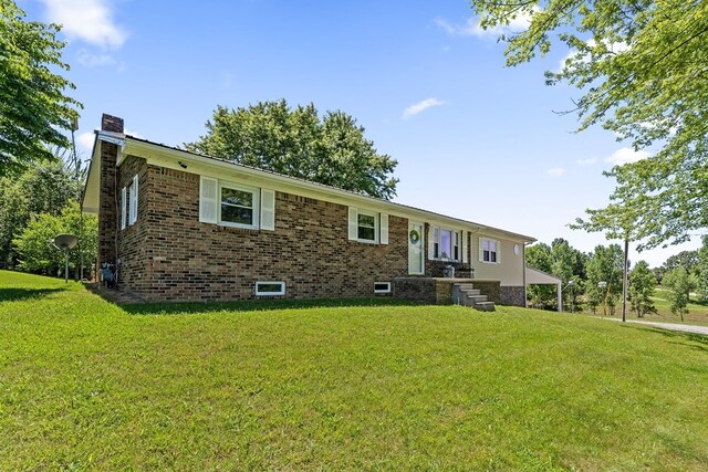 single story home with brick siding, a chimney, and a front yard