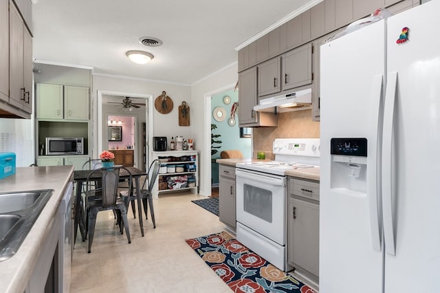 kitchen featuring white appliances, light countertops, crown molding, and under cabinet range hood