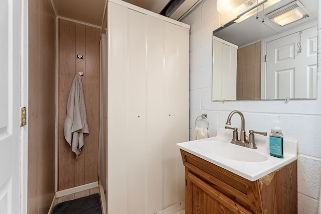 bathroom featuring concrete block wall, visible vents, and vanity