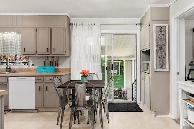 kitchen with ornamental molding, light countertops, white dishwasher, and a sink