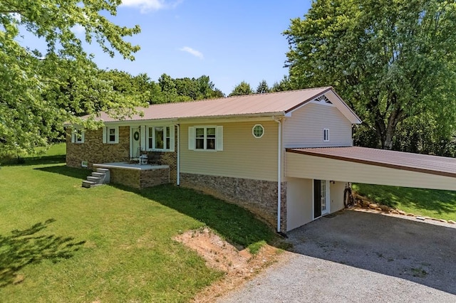 single story home featuring gravel driveway, a front yard, metal roof, a carport, and stone siding