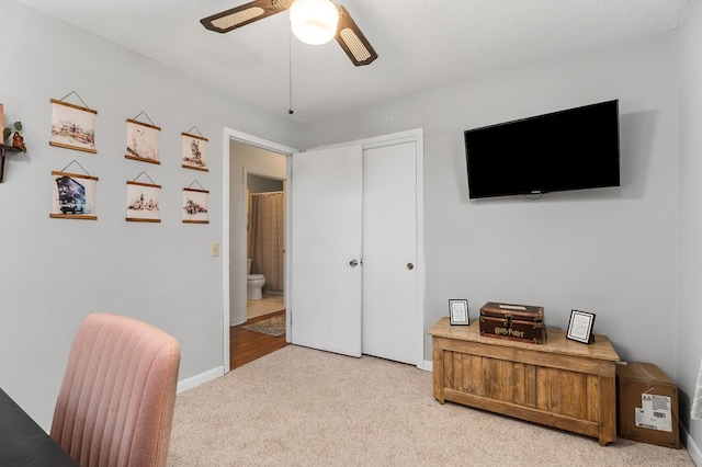 office area with a ceiling fan, light colored carpet, and baseboards