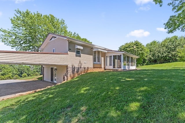 view of front of property with aphalt driveway, a sunroom, and a front lawn