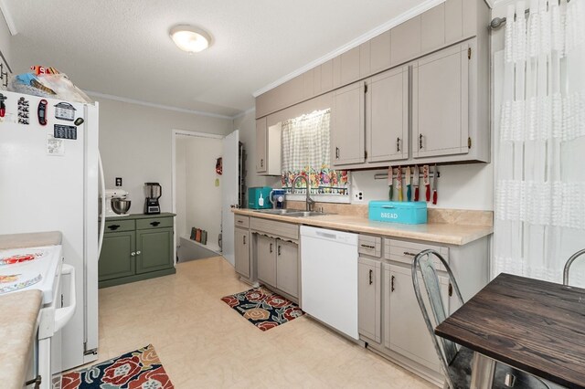 kitchen with white appliances, light countertops, crown molding, light floors, and a sink