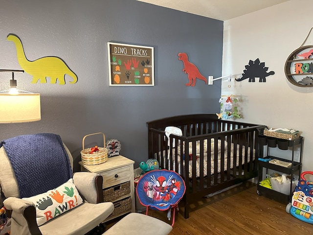 bedroom with a crib and wood finished floors