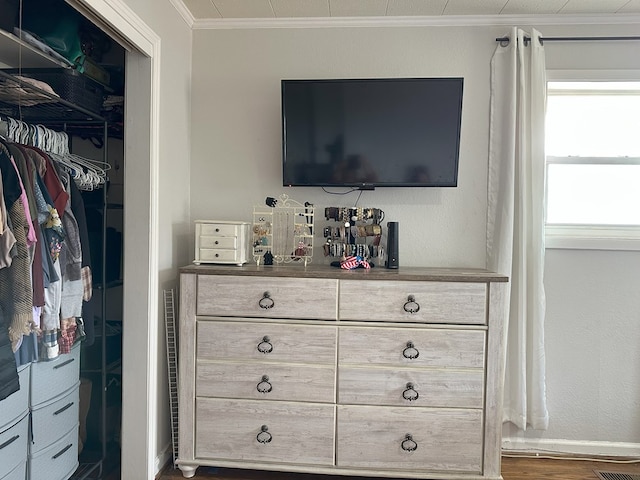 interior space with a closet, baseboards, wood finished floors, and crown molding