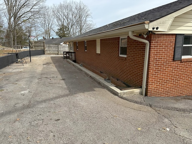 view of property exterior featuring brick siding, crawl space, and fence