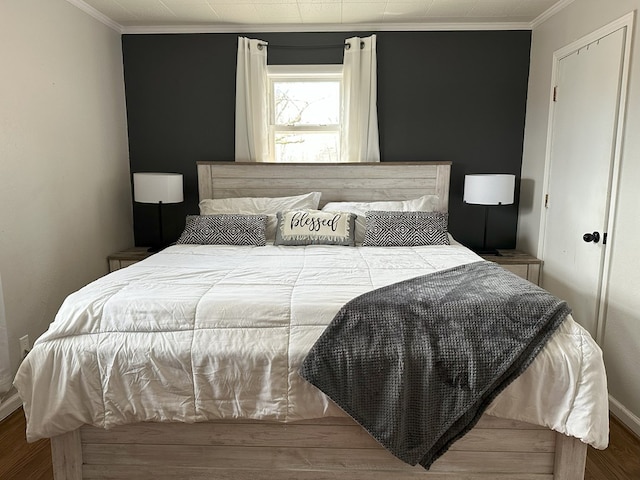 bedroom featuring wood finished floors, baseboards, and ornamental molding