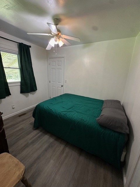 bedroom featuring ceiling fan, wood finished floors, visible vents, and baseboards