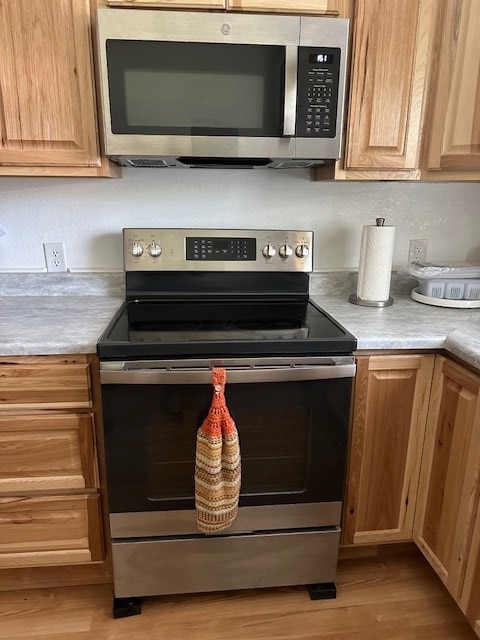 kitchen with appliances with stainless steel finishes, light countertops, and light wood-style flooring