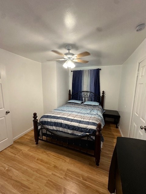 bedroom with light wood finished floors, baseboards, and a ceiling fan