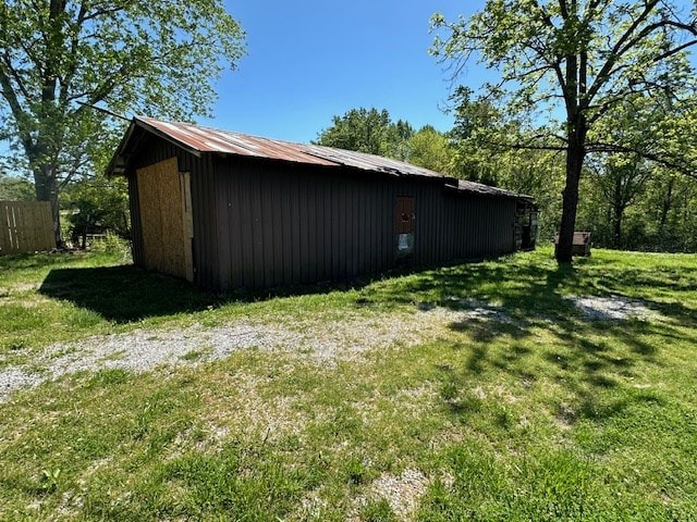 view of side of property with an outbuilding, a lawn, and fence