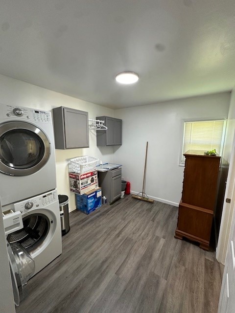 clothes washing area with cabinet space, stacked washing maching and dryer, and dark wood finished floors