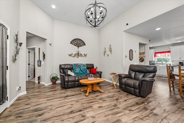 living room featuring recessed lighting, wood finished floors, baseboards, washer / dryer, and an inviting chandelier