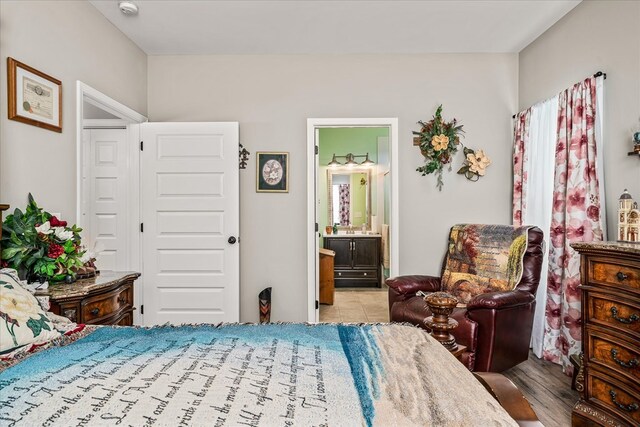 bedroom featuring ensuite bathroom and light wood finished floors