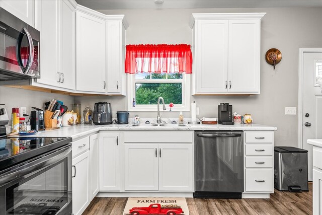 kitchen featuring a sink, stainless steel appliances, light countertops, and white cabinetry