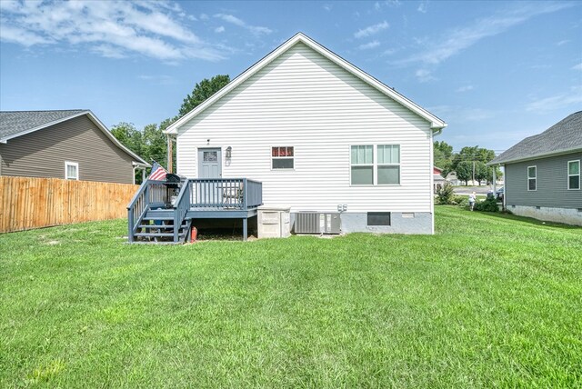 rear view of house with fence, a lawn, a deck, and cooling unit