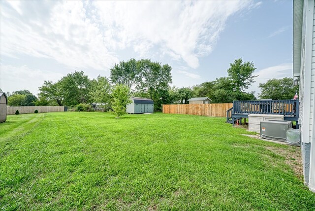 view of yard with a storage shed, an outdoor structure, a fenced backyard, and a wooden deck