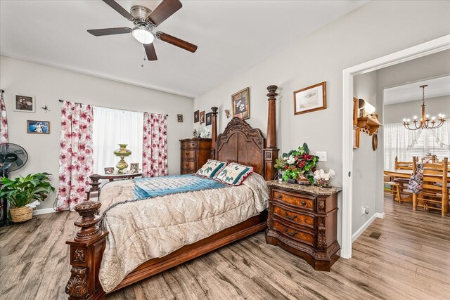 bedroom with light wood-style floors, baseboards, visible vents, and ceiling fan with notable chandelier