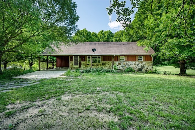 ranch-style house featuring an attached carport, driveway, stone siding, a front lawn, and board and batten siding